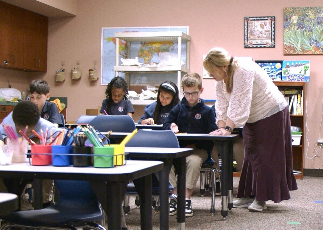 An American Classical Academy Rutherford teacher helping students at their desks