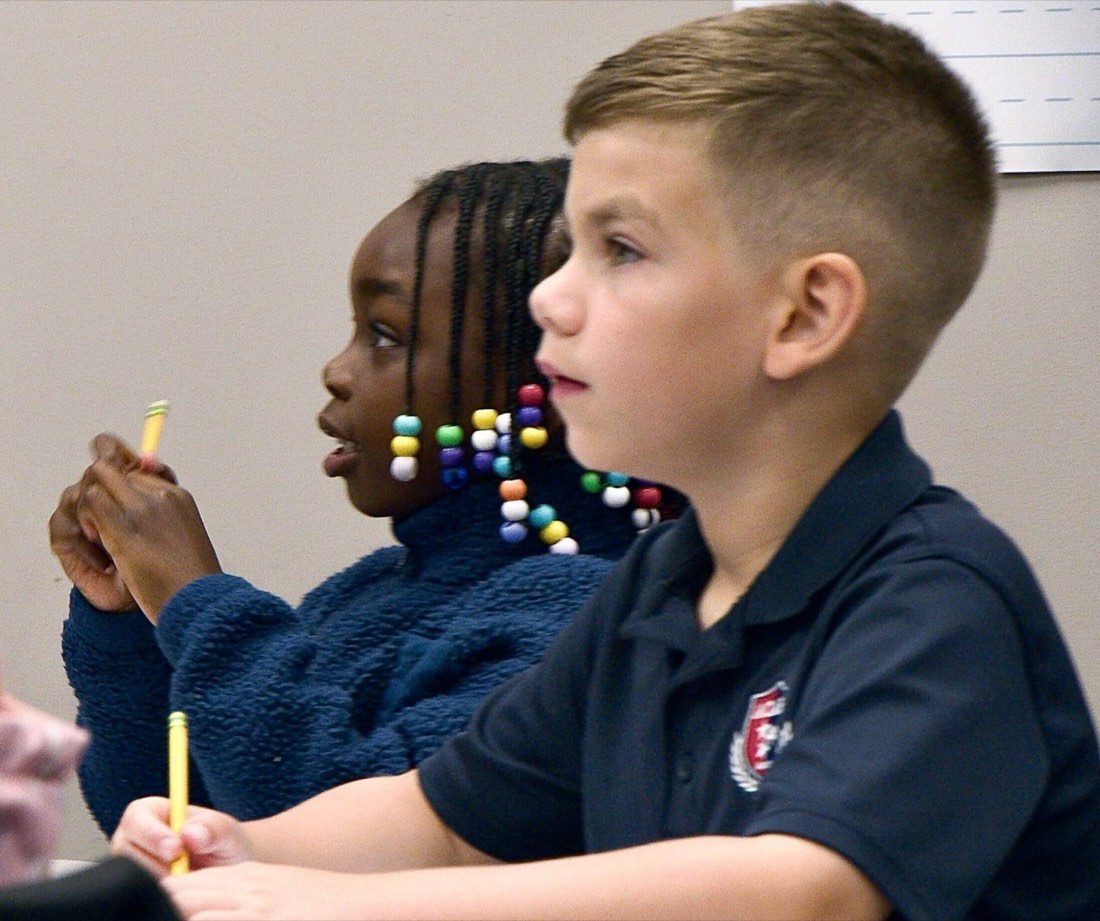Two ACAR students listening closely in class, pencils in hand